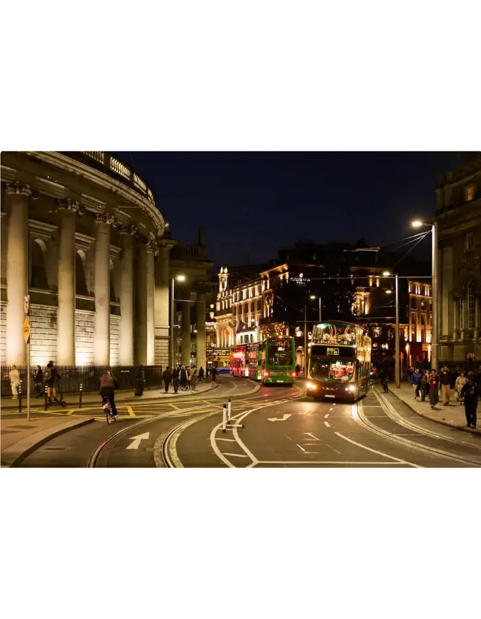 Dublin Bus double-deckers on College Green in Dublin city centre at night, near The Dawson Hostel